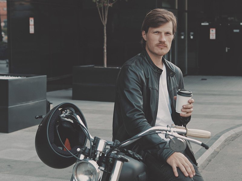 Guy drinking coffee sat on bike